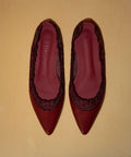 Pair of red pointed-toe shoes with decorative lace patterns 