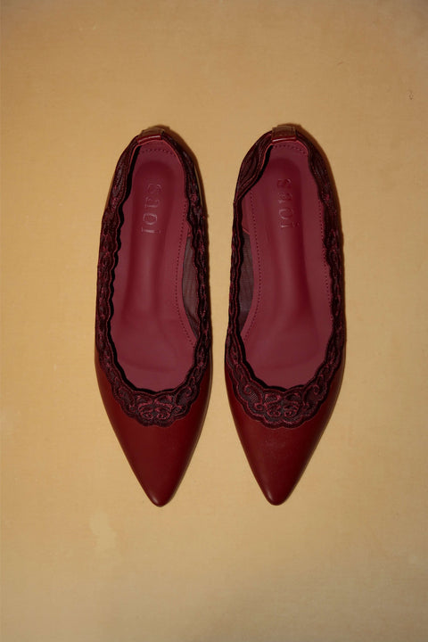 Pair of red pointed-toe shoes with decorative lace patterns 